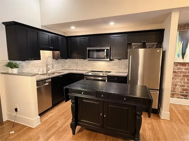 a kitchen with stainless steel appliances wooden cabinets a refrigerator and a sink