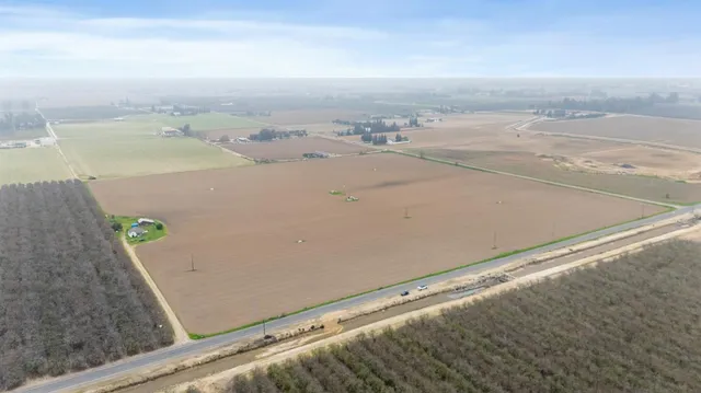 a view of a lake with chairs and table on the side
