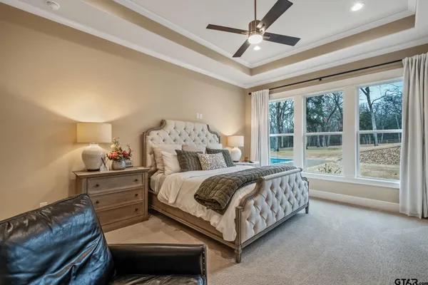 a bedroom with a large bed and a chandelier fan