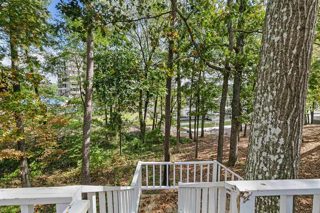 a view of a house with large tree and wooden fence