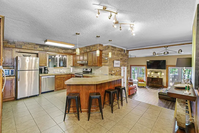 a kitchen with stainless steel appliances a sink counter space and chairs in it