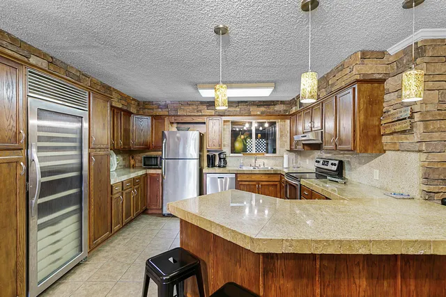 a kitchen with stainless steel appliances granite countertop a sink refrigerator and cabinets