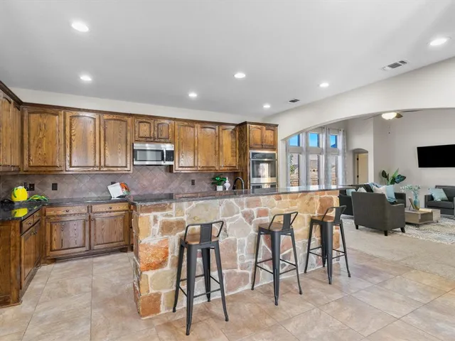 a kitchen with stainless steel appliances granite countertop table chairs sink and cabinets