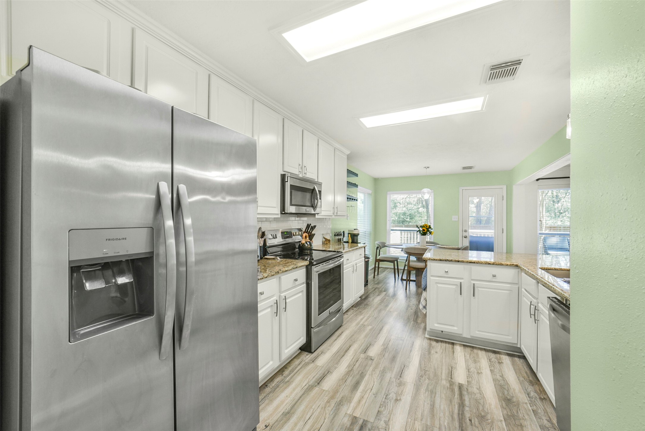 38 Tallow Hill Place Spring, TX 77382 - Photo 12 of 50 a kitchen with stainless steel appliances a refrigerator a sink dishwasher a stove and white cabinets with wooden floor