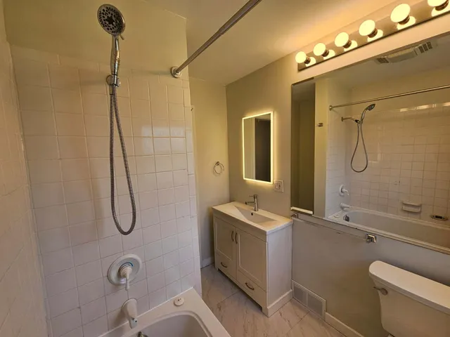 a bathroom with a granite countertop sink a toilet and shower