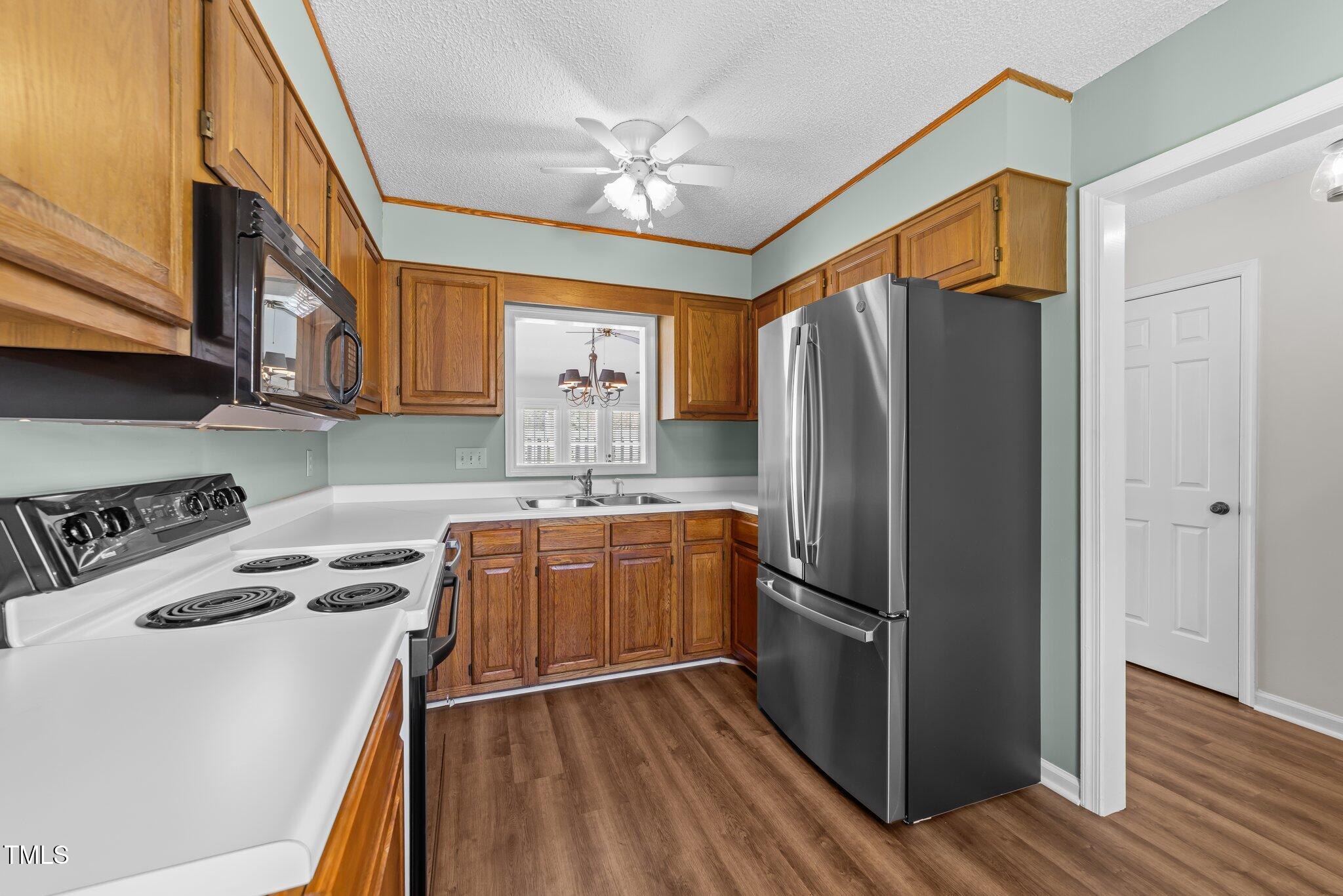 6817 Fairpoint Court Raleigh, NC 27613 - Photo 6 of 25 a kitchen with stainless steel appliances granite countertop a refrigerator a stove and a sink with wooden floor