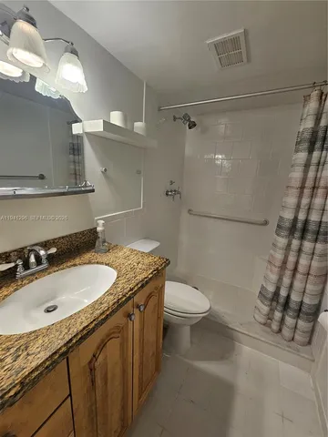 a bathroom with a granite countertop sink toilet and shower