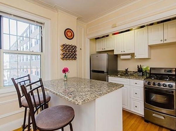 1450 Beacon Street, Unit 504 Brookline, MA 02446 - Photo 2 of 21 a kitchen with granite countertop a stove a sink dishwasher a dining table and chairs with wooden floor
