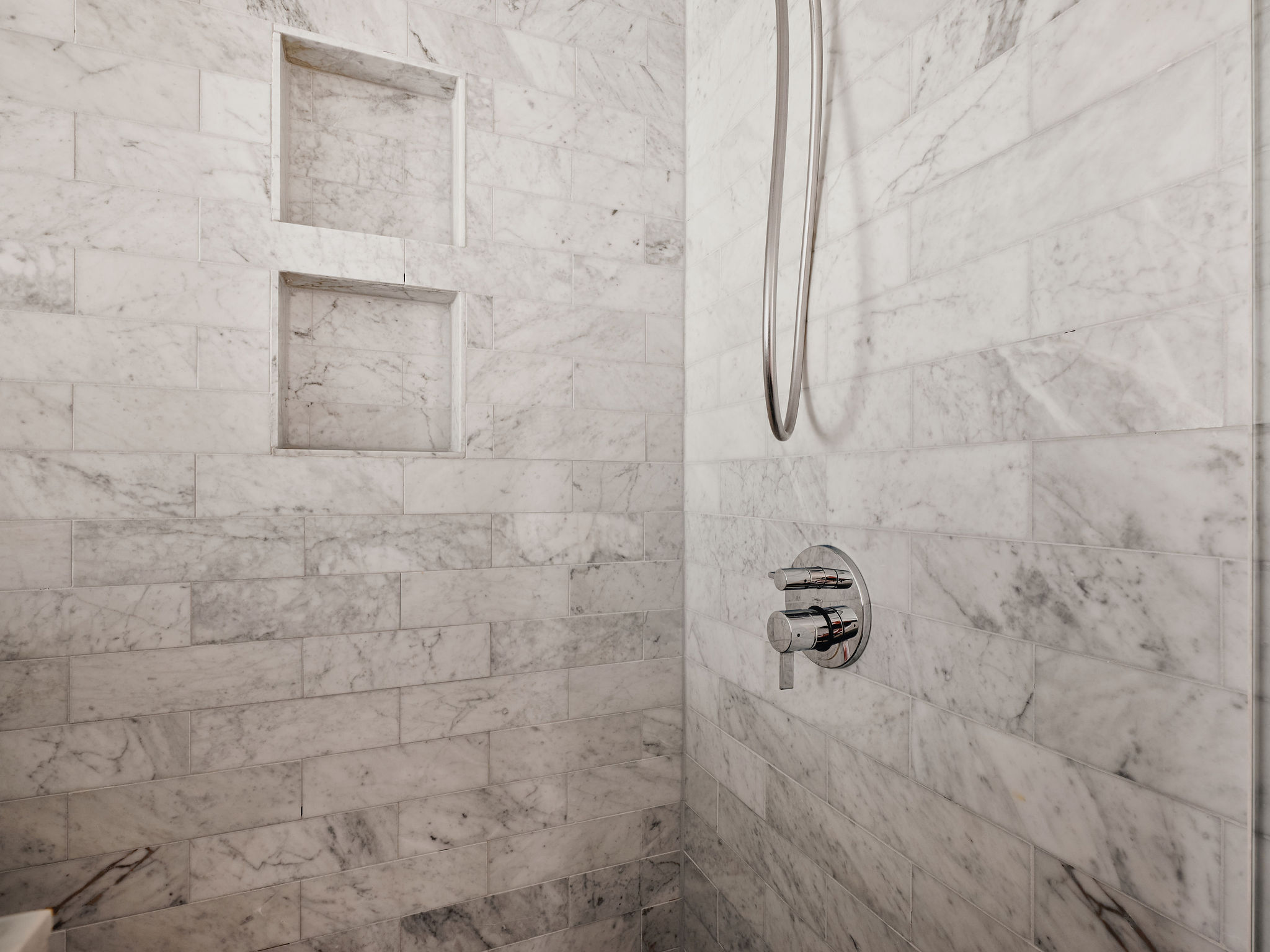 Undisclosed Address Austin, TX 78731 - Photo 16 of 26 Marble-tiled shower features dual built-in niches and sleek modern fixtures.