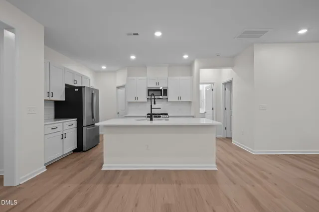 a view of kitchen with kitchen island a sink wooden floor and a refrigerator