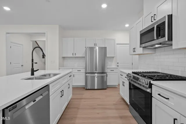 a kitchen with stainless steel appliances granite countertop a sink a stove and a microwave