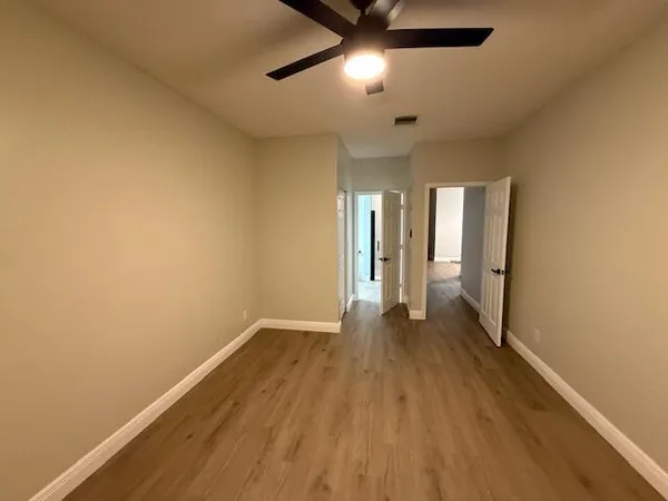 an empty room with wooden floor and a ceiling fan