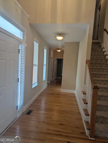 a view of an empty room with wooden floor and a window