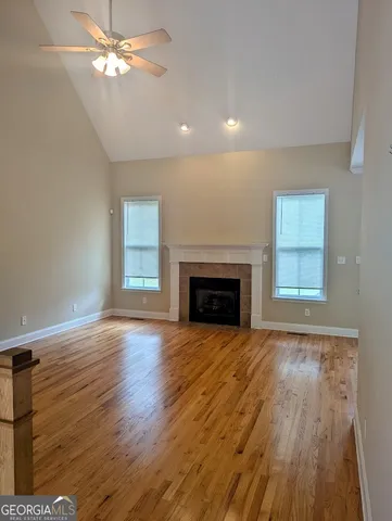 a view of empty room with wooden floor and fan