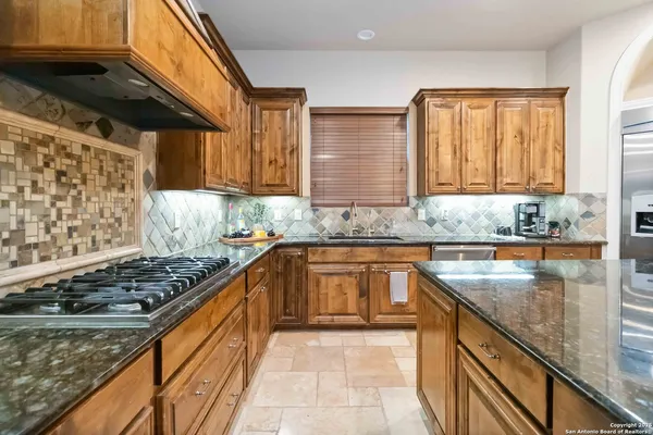 a kitchen with granite countertop a sink a counter top space and cabinets