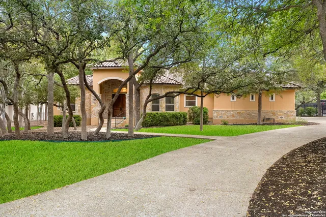 a view of a house with a big yard and large trees