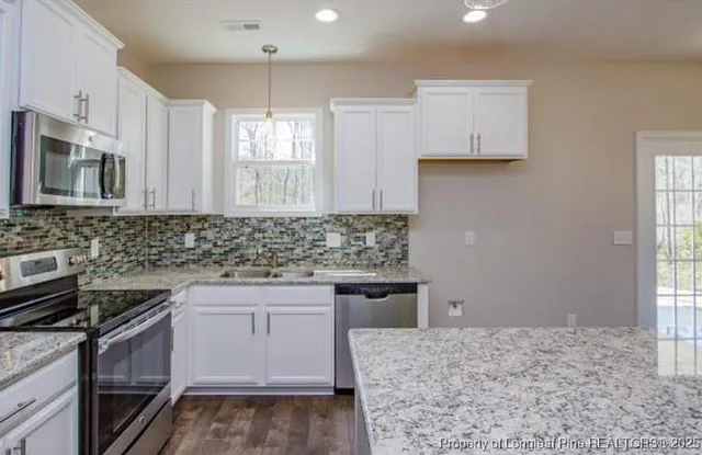 a kitchen with kitchen island granite countertop a sink stove and cabinets