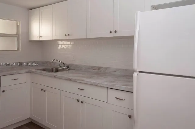 a kitchen with granite countertop white cabinets and white appliances