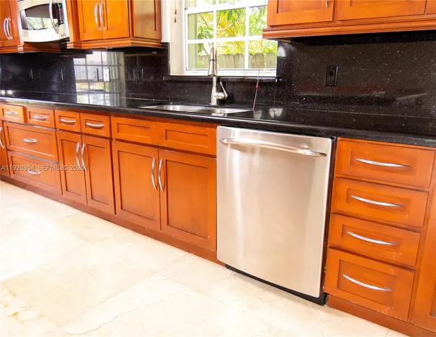 a kitchen with granite countertop cabinets stainless steel appliances and a sink