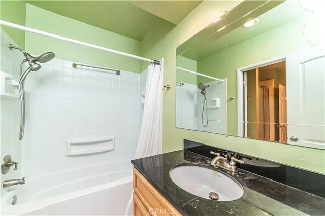 a bathroom with a granite countertop sink a mirror a shower and a bathtub