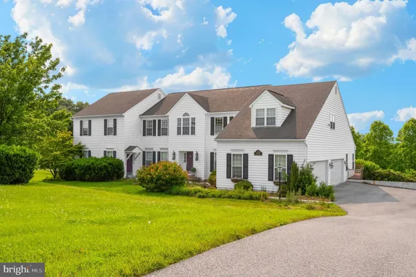a front view of a house with garden and trees