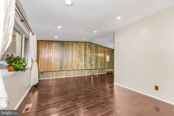 an empty room with wooden floor and mirror