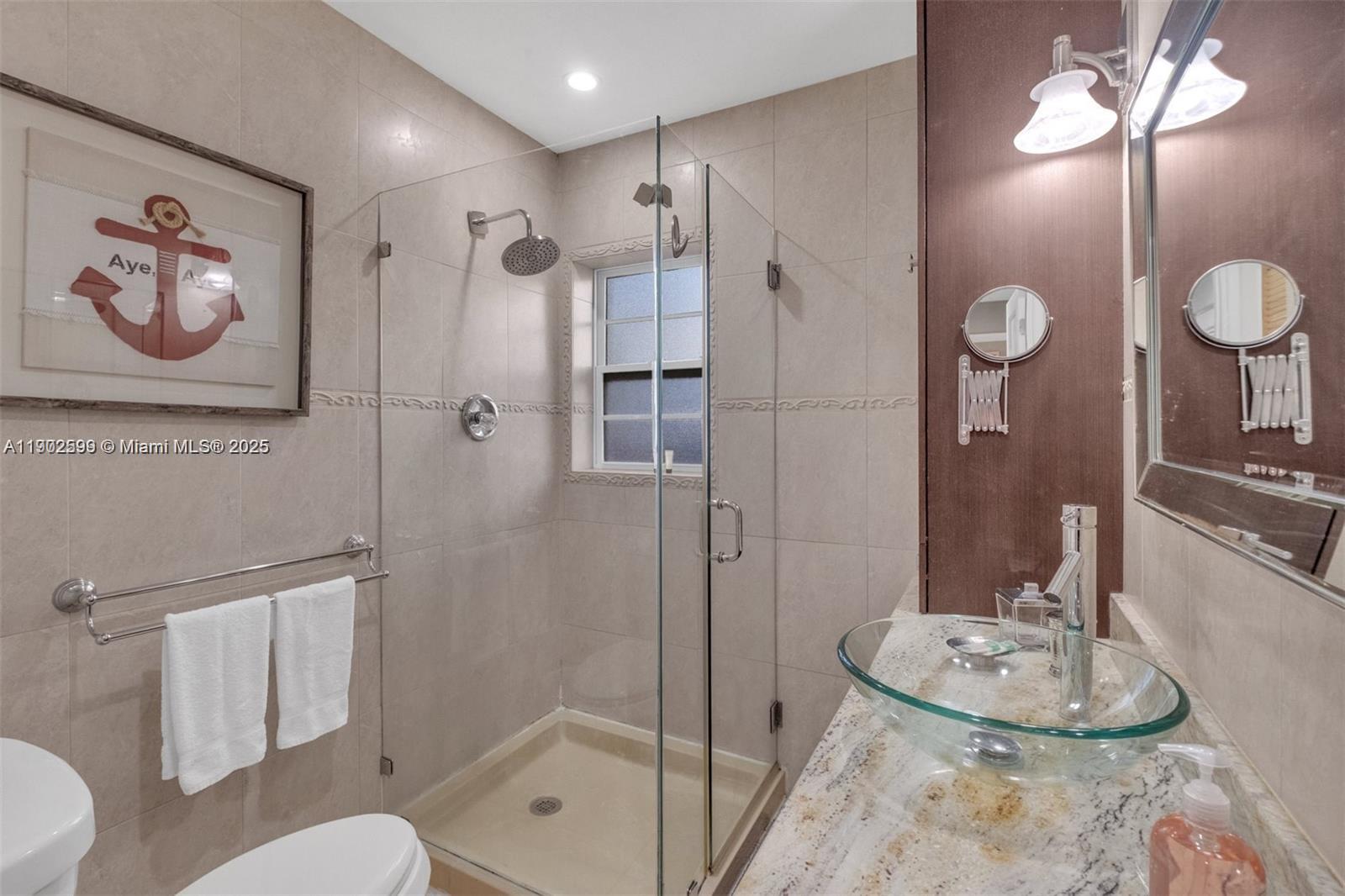 1033 Northwest 6 Street, Unit A Miami, FL 33136 - Photo 13 of 35 a bathroom with a granite countertop sink a toilet a mirror and shower