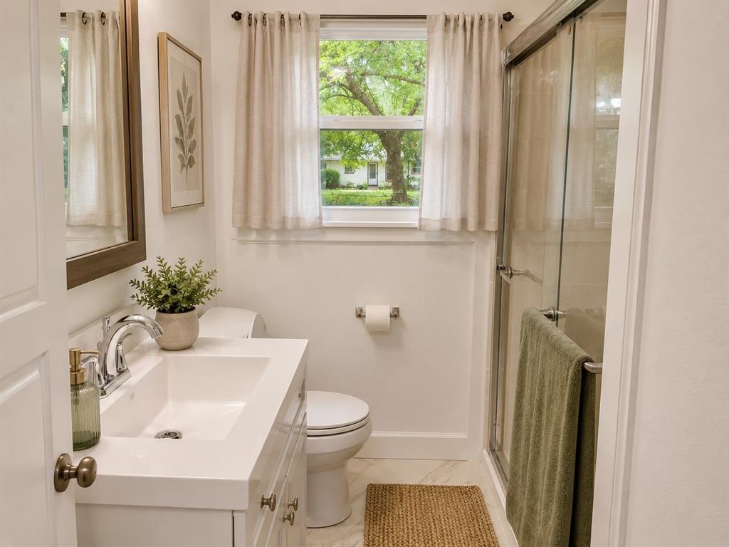 1109 North Howeth Street Gainesville, TX 76240 - Photo 8 of 11 Bathroom featuring a white vanity with an integrated sink, polished chrome faucet, and a framed mirror