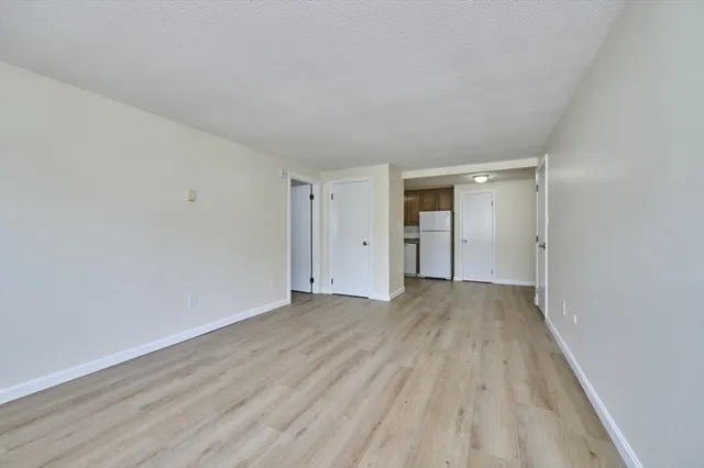 a view of an empty room with wooden floor and closet