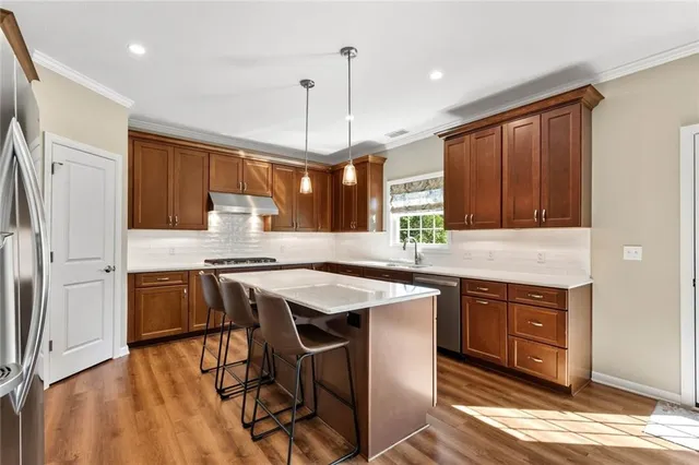 a kitchen with stainless steel appliances granite countertop wooden floors a stove a sink and a refrigerator