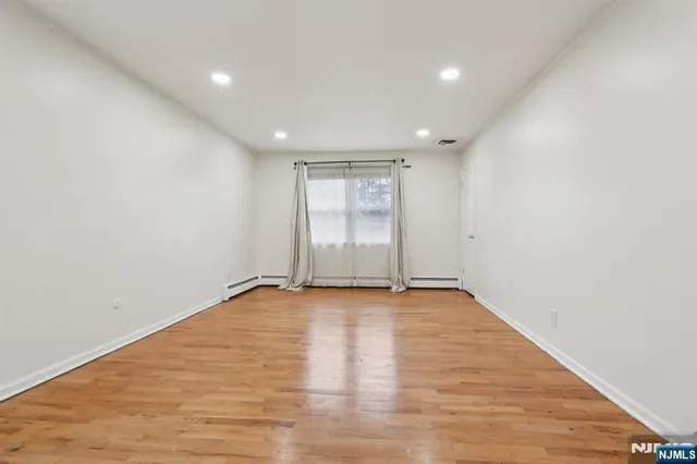 a view of an empty room with wooden floor and window