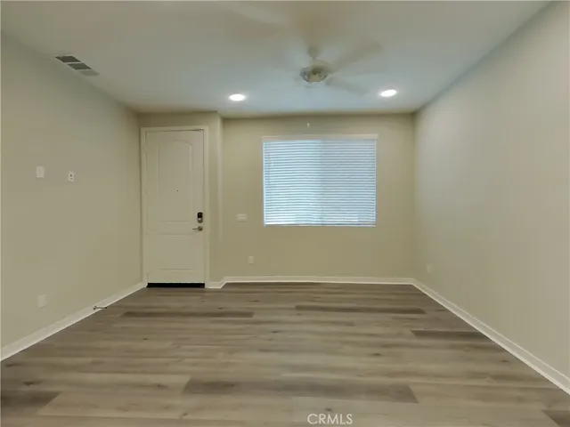 an empty room with wooden floor and windows