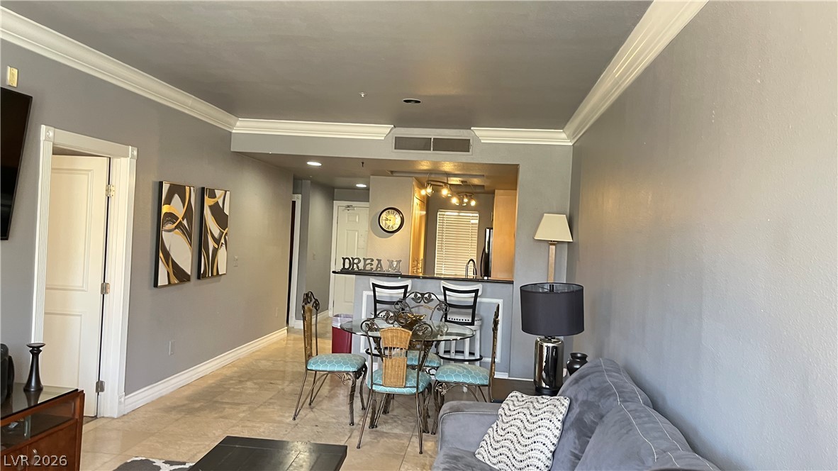 210 East Flamingo Road, Unit 205 Las Vegas, NV 89169 - Photo 7 of 17 Elegant crown molding adorns this combined living and dining space with natural tile flooring.