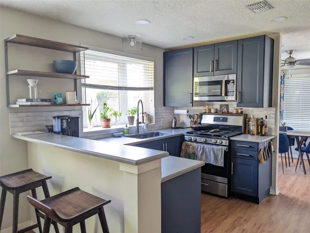 a kitchen with kitchen island granite countertop a stove top oven a sink dishwasher a dining table and chairs with wooden floor