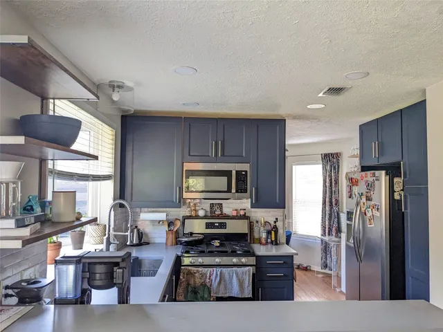 a kitchen with stainless steel appliances a refrigerator and a stove top oven