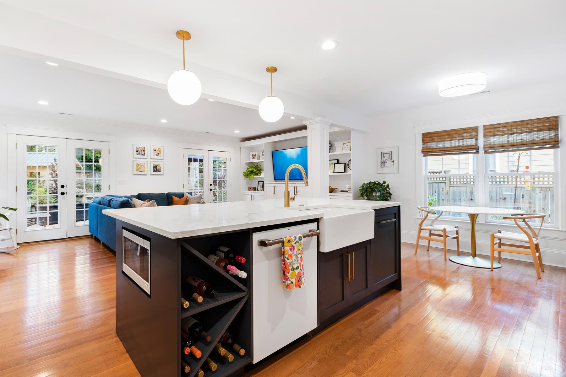 308 Perry Street Raleigh, NC 27608 - Photo 12 of 30 a living room with stainless steel appliances kitchen island granite countertop a large kitchen island a stove a sink a dining table and chairs with wooden floor