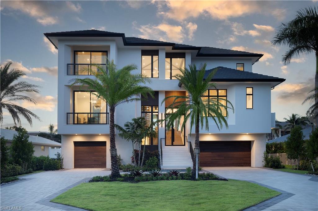 141 Channel Drive Naples, FL 34108 - Photo 1 of 28 View of front facade featuring a balcony, an attached garage, stucco siding, and driveway