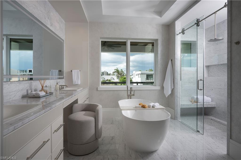 141 Channel Drive Naples, FL 34108 - Photo 18 of 28 Full bath with a stall shower, double vanity, a freestanding bath, marble look tile flooring, and ceiling fan
