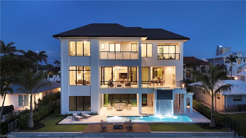 141 Channel Drive Naples, FL 34108 - Photo 27 of 28 Back of house at twilight featuring a balcony, stucco siding, a patio, and an outdoor pool