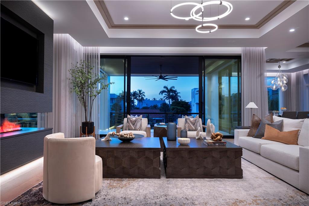 141 Channel Drive Naples, FL 34108 - Photo 3 of 28 Living room with a tray ceiling, a chandelier, and a ceiling fan