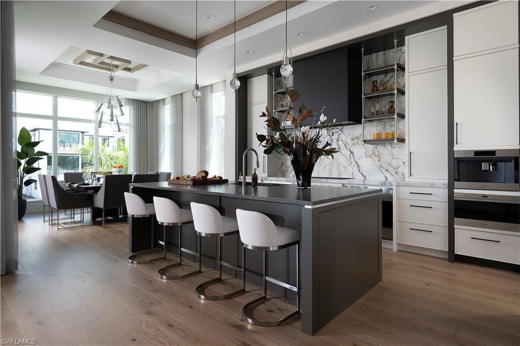 141 Channel Drive Naples, FL 34108 - Photo 6 of 28 Kitchen with a breakfast bar, a tray ceiling, open shelves, dark countertops, and dark wood-style flooring