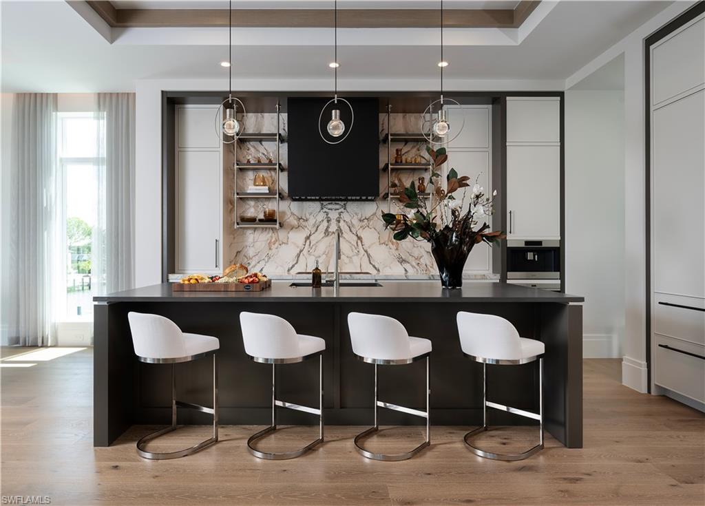 141 Channel Drive Naples, FL 34108 - Photo 7 of 28 Bar area featuring a raised ceiling, tasteful backsplash, extractor fan, stainless steel oven, and light wood finished floors