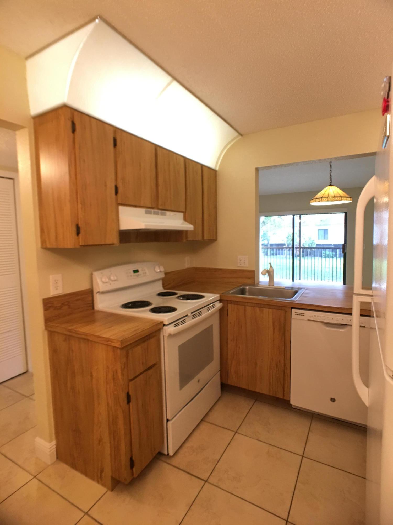 23398 Southwest 57th Avenue, Unit 309 Boca Raton, FL 33428 - Photo 11 of 29 a kitchen with a stove a sink and a refrigerator