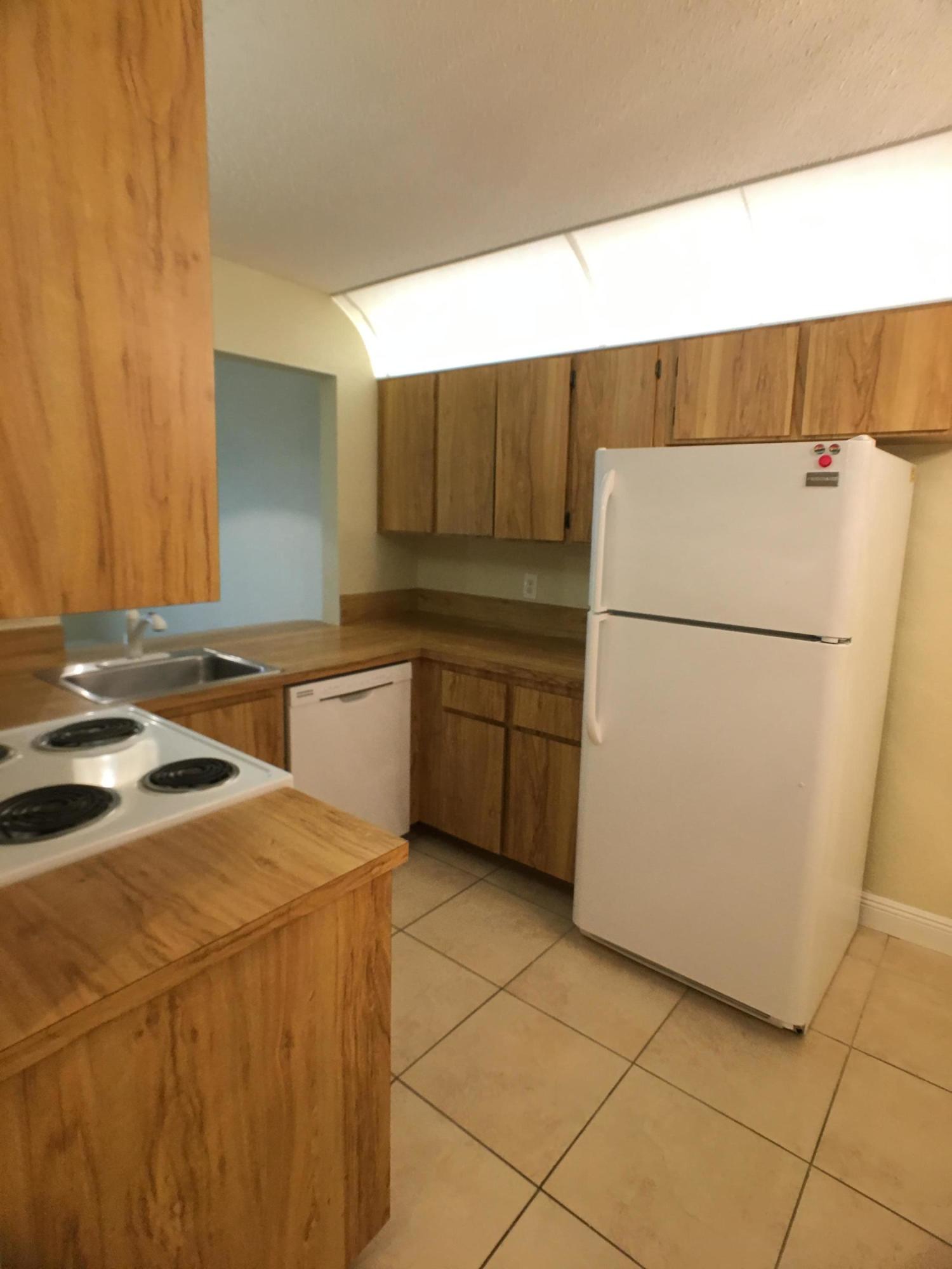 23398 Southwest 57th Avenue, Unit 309 Boca Raton, FL 33428 - Photo 13 of 29 a kitchen with a sink a refrigerator and a stove top oven