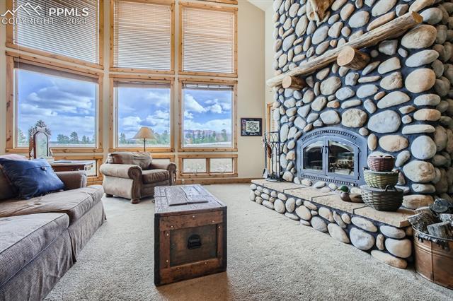 182 Joshua Road Divide, CO 80814 - Photo 4 of 35 Living room featuring a high ceiling, carpet floors, and a stone fireplace