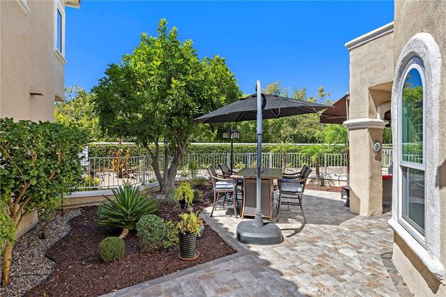 a view of a patio with table and chairs potted plants and floor to ceiling window