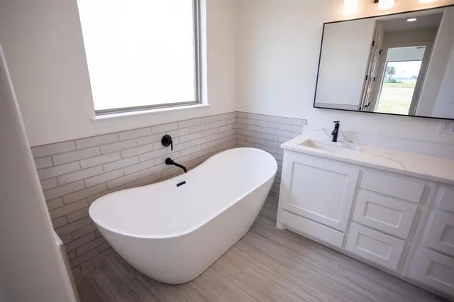 an empty room with wooden floor ceiling fan and windows