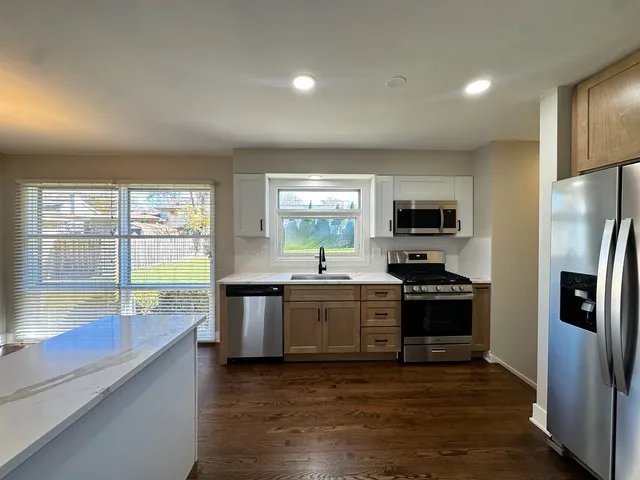 a large kitchen with stainless steel appliances granite countertop a stove a sink and a refrigerator