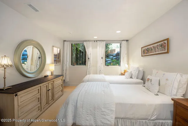 a bedroom with a bed a mirror on the dresser and a window