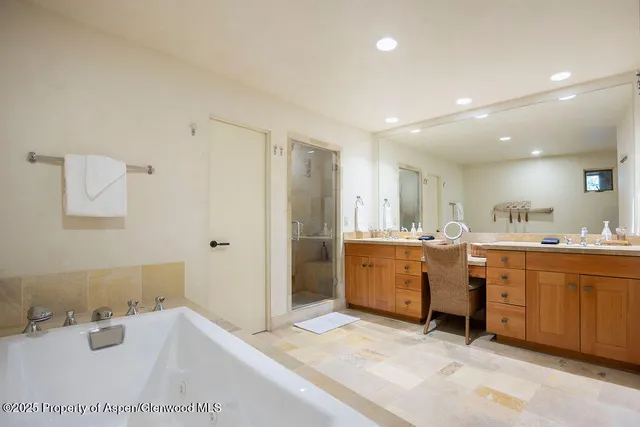 a large bathroom with a tub sink and mirror